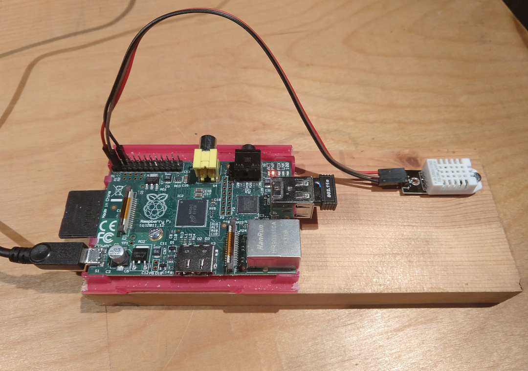 This is a photo of the Raspberry Pi 2 I use to make humidity and temperature readings from the DHT22 sensor that is attached to it available to other computers on my network. Since this is a Pi 2, and not a Pi 3 B+ as I describe in the write-up that follows, I had to add a USB wifi adapter to it so that it could connect to the wifi network in my home. The GPIO pin layout is also different on a Pi 2 vs a Pi 3.